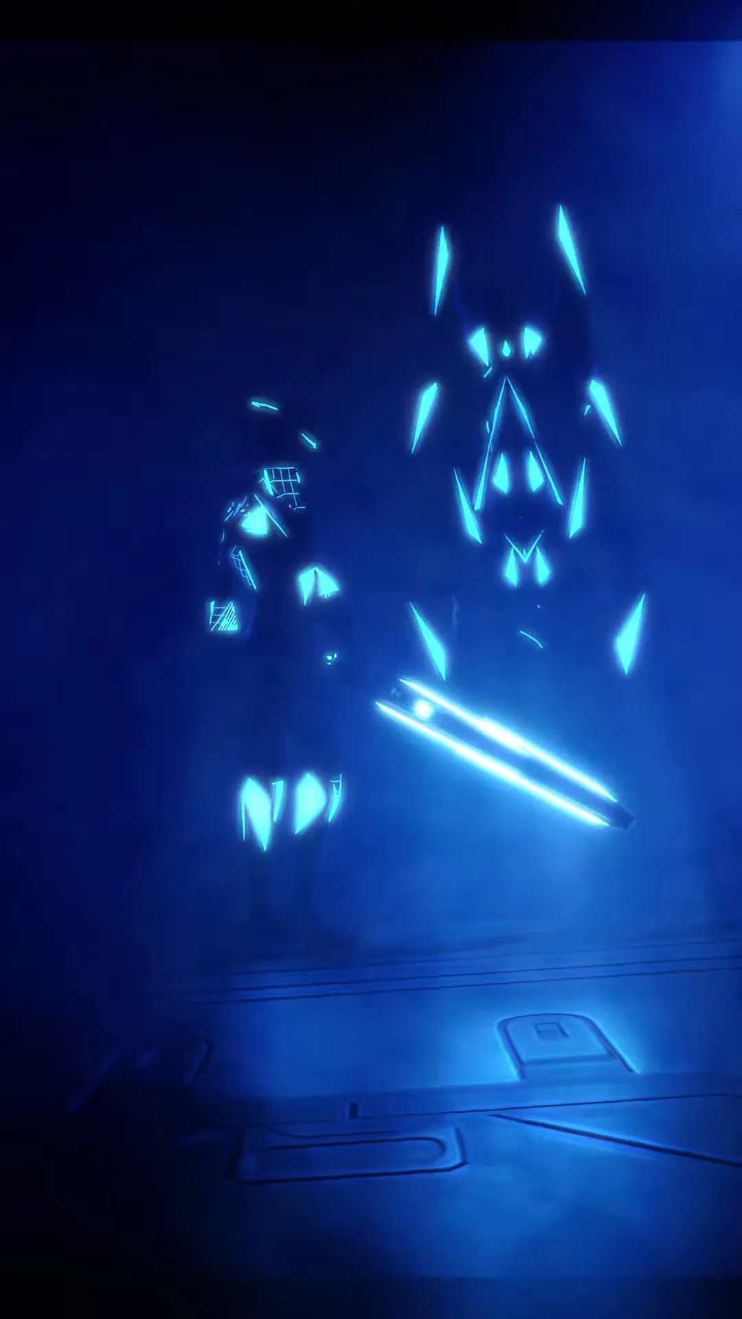 Glowing blue light shapes forming in darkness.